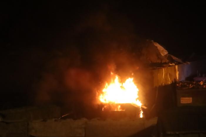 Grote berg afvalhout in brand naast houtopslag