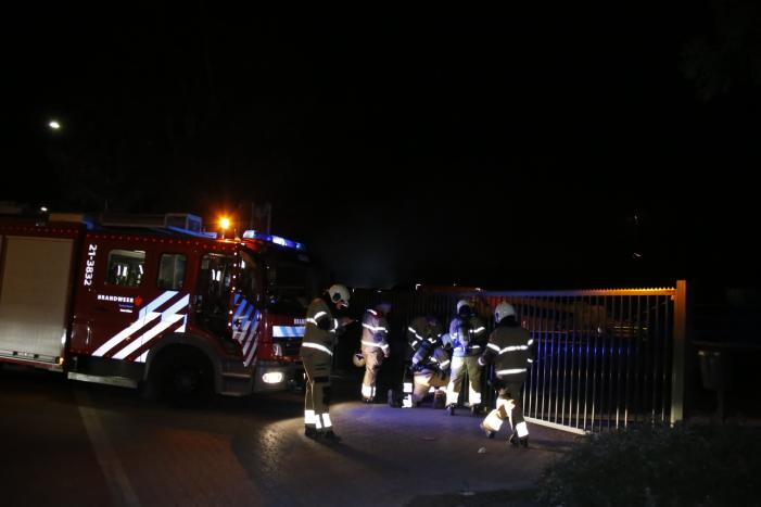 Grote berg afvalhout in brand naast houtopslag