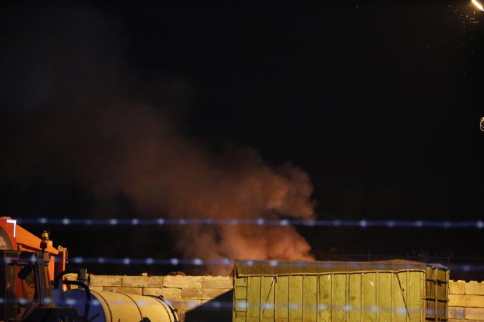 Grote berg afvalhout in brand naast houtopslag