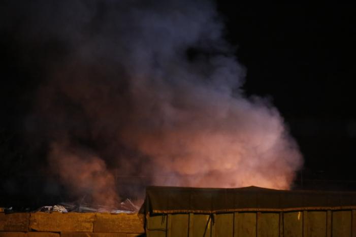 Grote berg afvalhout in brand naast houtopslag