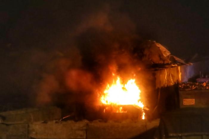 Grote berg afvalhout in brand naast houtopslag