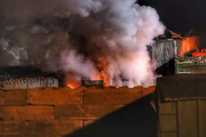 Grote berg afvalhout in brand naast houtopslag