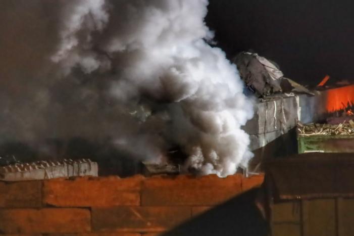 Grote berg afvalhout in brand naast houtopslag