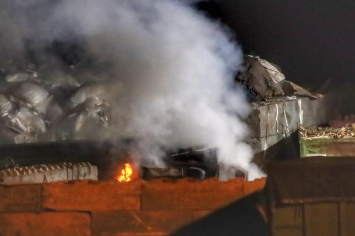 Grote berg afvalhout in brand naast houtopslag