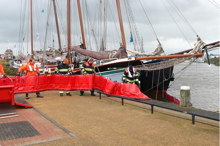 Brandweer plaats olieschermen voor lekkend zeilschip