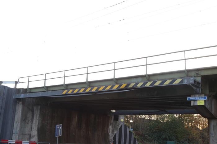 Vrachtwagen met graafmachine ramt spoorbrug