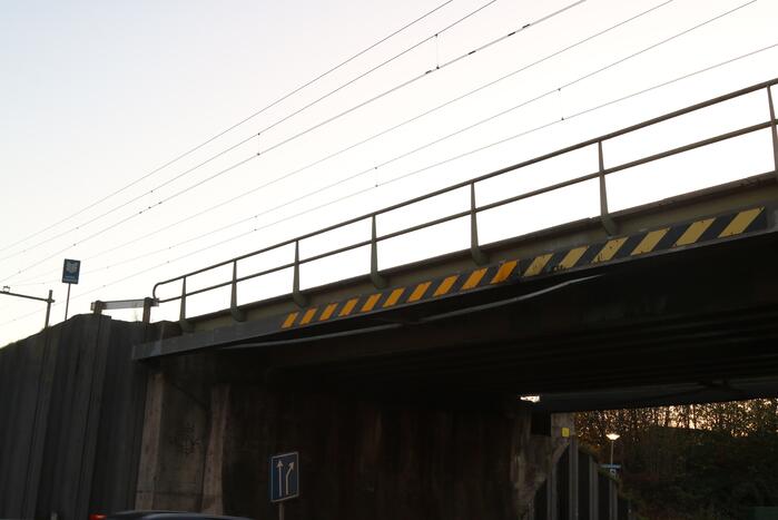 Vrachtwagen met graafmachine ramt spoorbrug