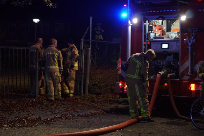 Berg afval in brand achter schoolgebouw