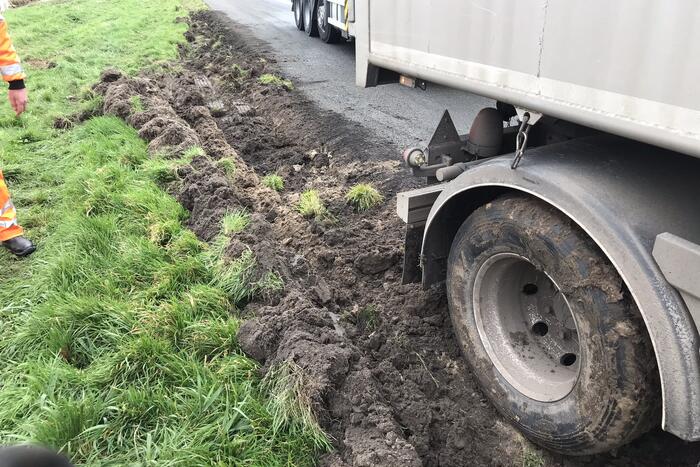Vrachtwagen rijdt zich vast in berm langs snelweg