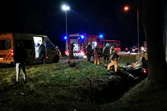 Personenauto ligt op zijn kop in berm