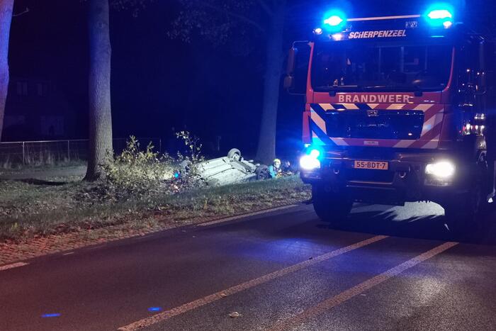 Personenauto ligt op zijn kop in berm