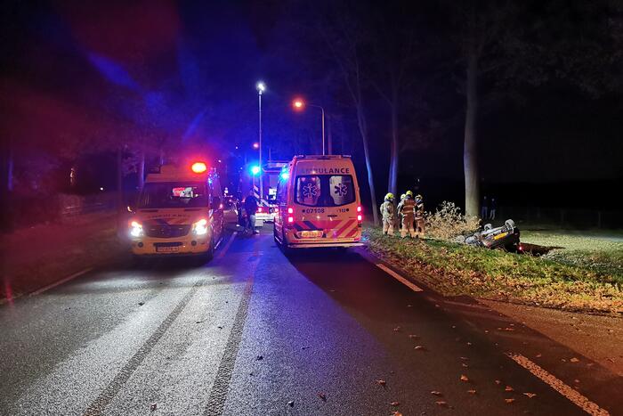 Personenauto ligt op zijn kop in berm