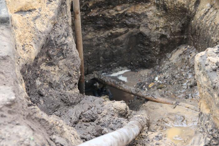 Straat opengebroken door gesprongen waterleiding in Smitsveen