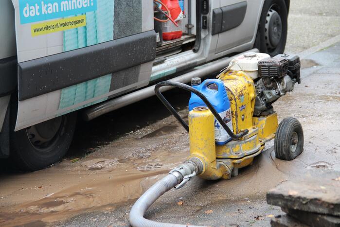 Straat opengebroken door gesprongen waterleiding in Smitsveen