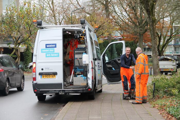 Straat opengebroken door gesprongen waterleiding in Smitsveen