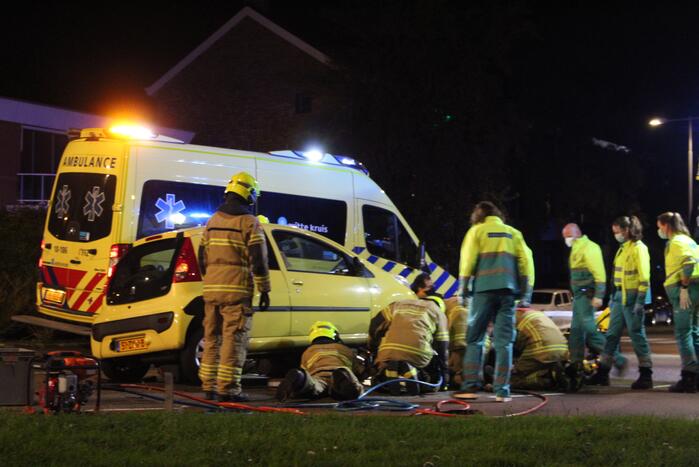 Fietser bekneld onder auto