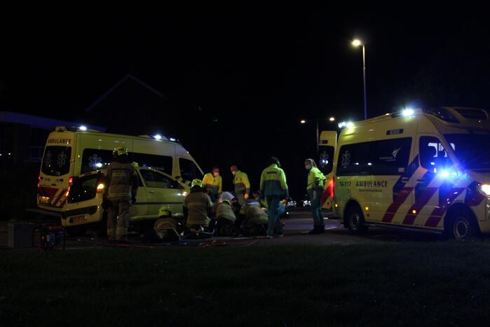 Fietser bekneld onder auto