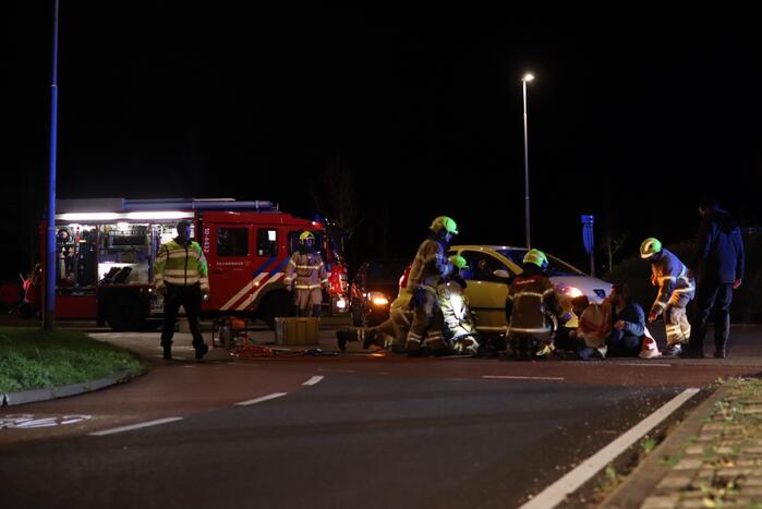 Fietser bekneld onder auto
