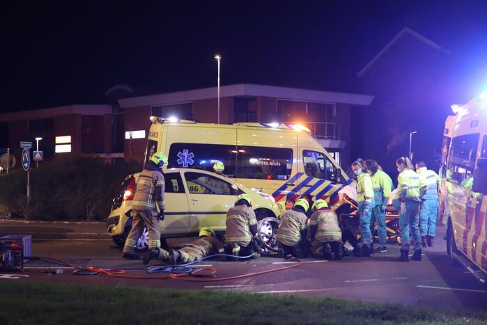 Fietser bekneld onder auto