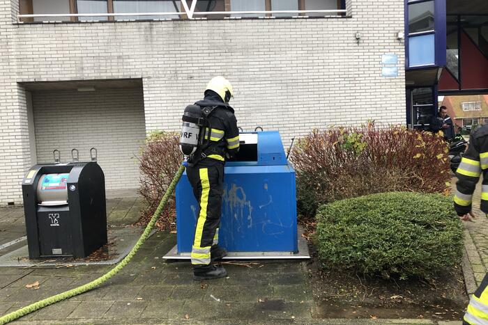 Omstanders blussen brand in papiercontainer