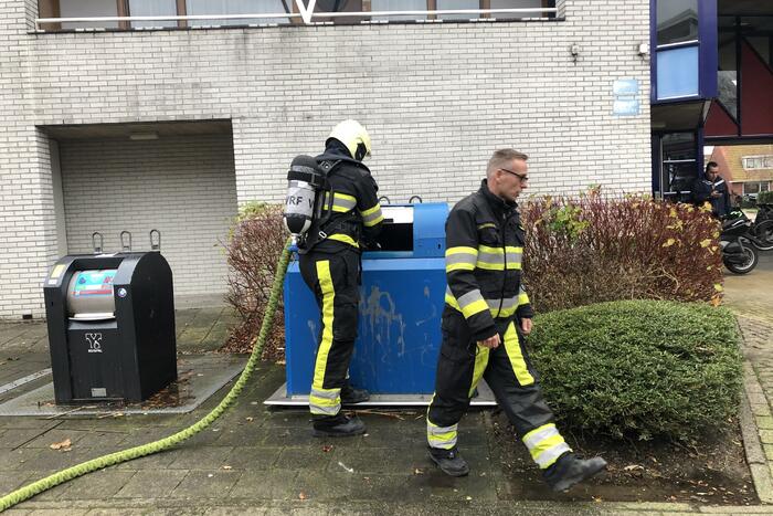 Omstanders blussen brand in papiercontainer