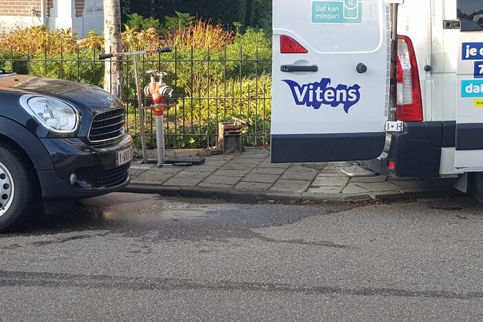 Straat opengebroken door gesprongen waterleiding