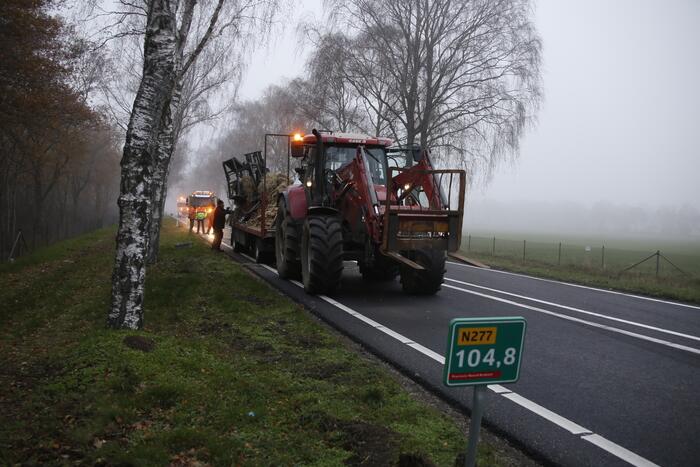 Vrachtwagen met aanhanger met hooi ramt boom