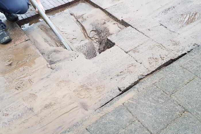 Leidingbreuk zorgt voor zand en water over de weg