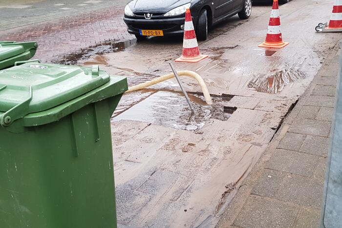 Leidingbreuk zorgt voor zand en water over de weg