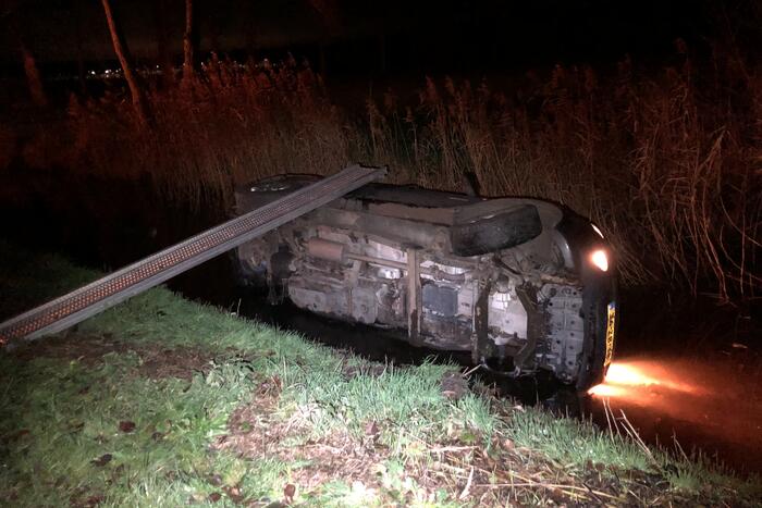 Auto vliegt uit de bocht en belandt op zijn kant in sloot