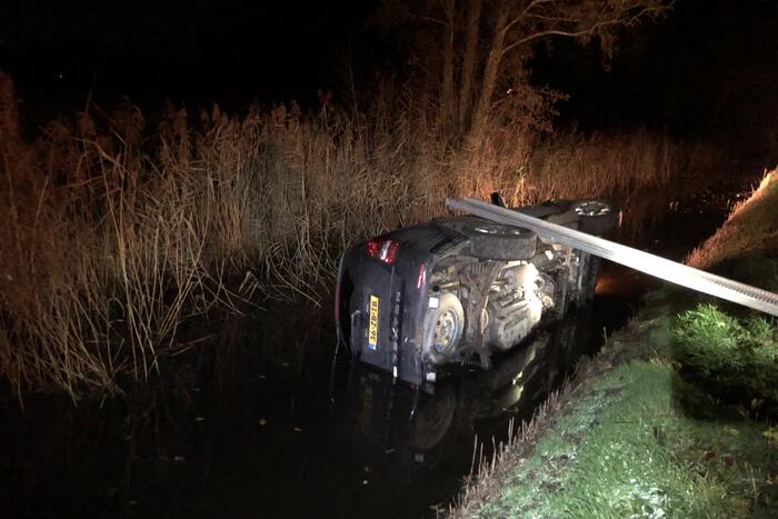 Auto vliegt uit de bocht en belandt op zijn kant in sloot