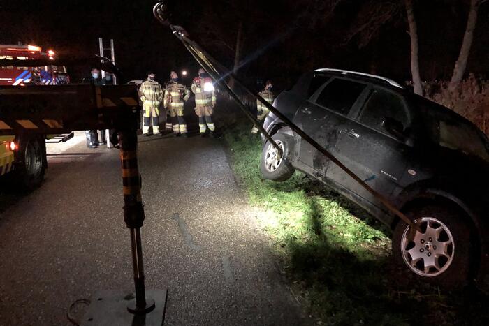 Auto vliegt uit de bocht en belandt op zijn kant in sloot
