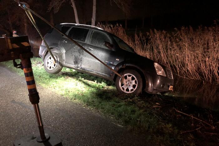 Auto vliegt uit de bocht en belandt op zijn kant in sloot