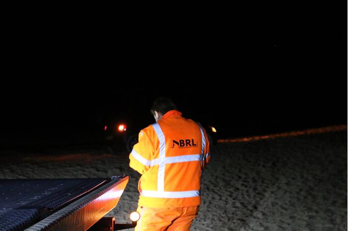 Automobilist rijdt auto vast op strand