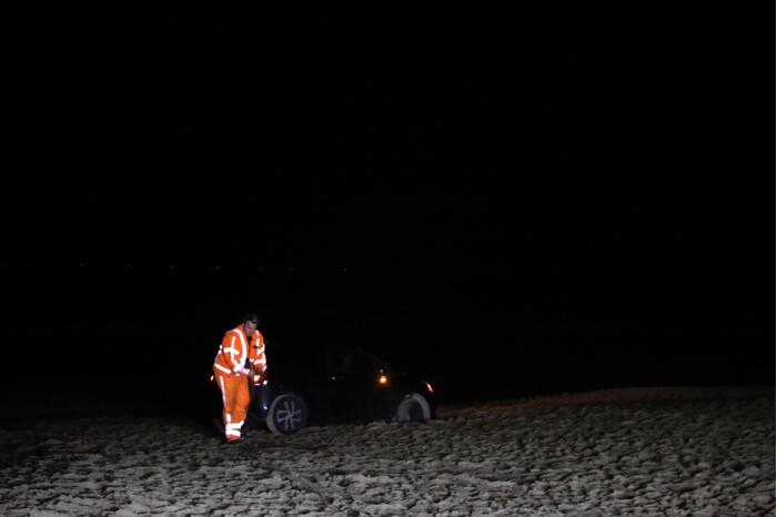 Automobilist rijdt auto vast op strand