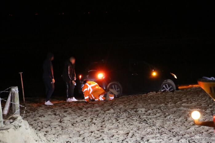 Automobilist rijdt auto vast op strand