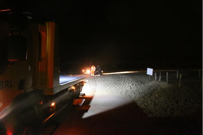Automobilist rijdt auto vast op strand