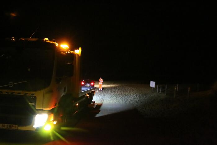Automobilist rijdt auto vast op strand