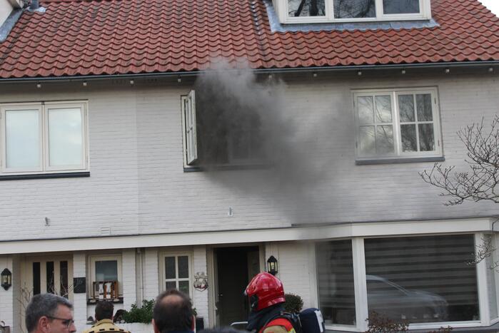Zwarte rookwolken uit woning