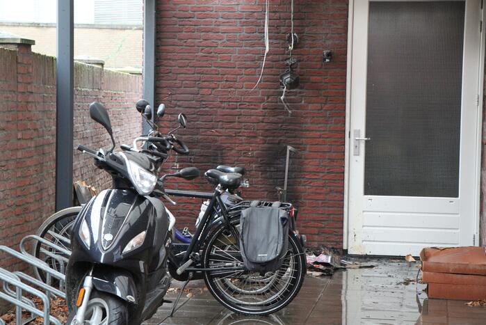 Brand onder overkapping van woning