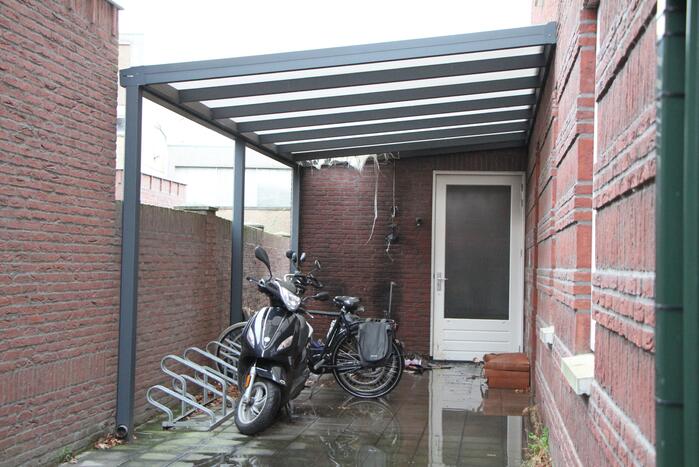 Brand onder overkapping van woning