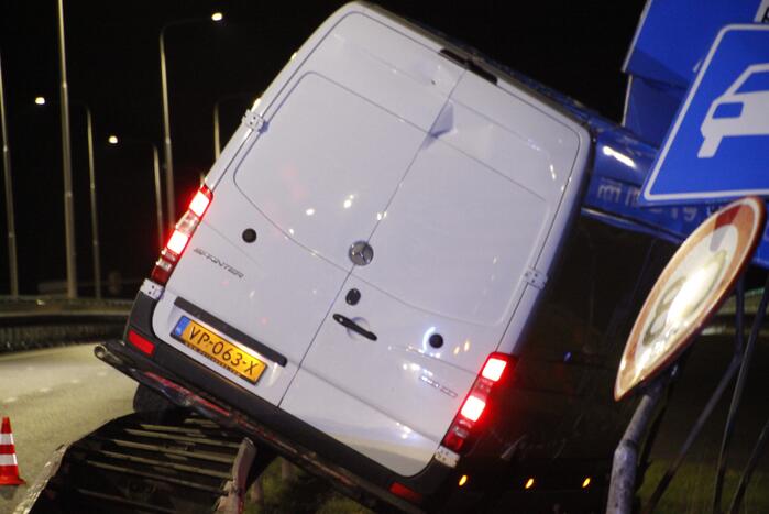 Bestelbus rijdt op vangrail en raakt verkeersborden