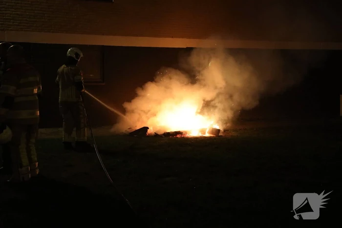 Hout en afval in brand tegen gevel
