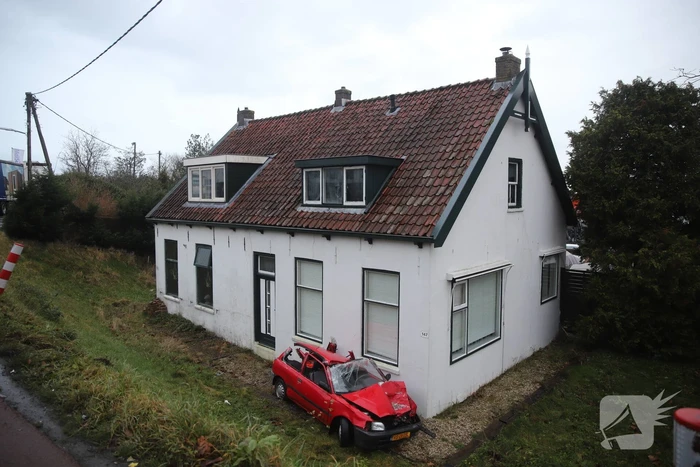 Auto rijdt van dijk en knalt tegen woning