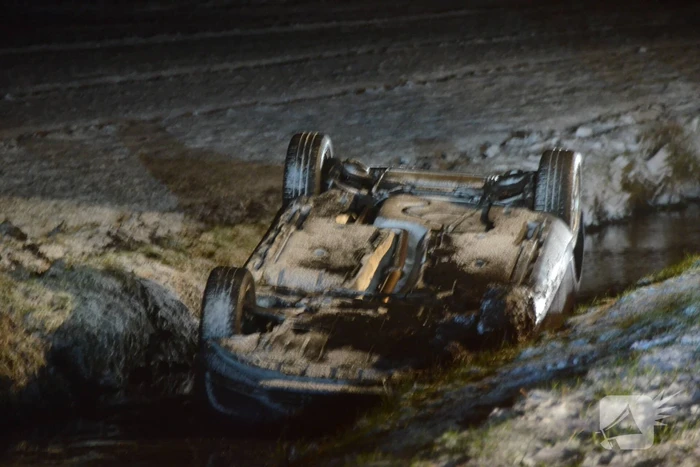 Auto glijdt van de weg en belandt op de kop in sloot