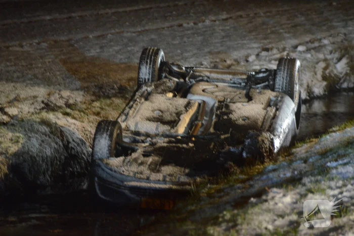 Auto glijdt van de weg en belandt op de kop in sloot