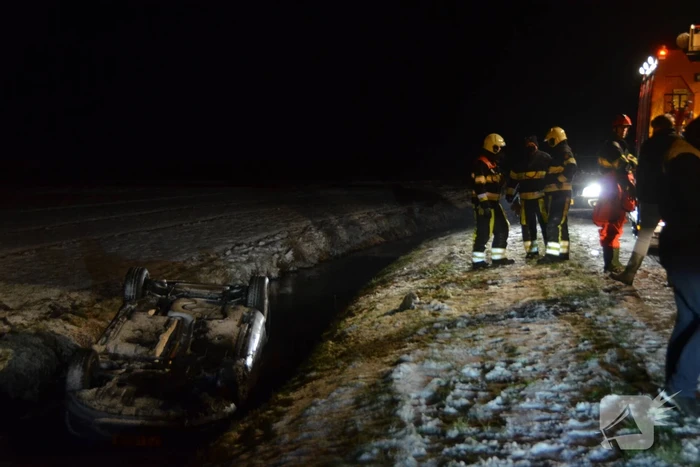 Auto glijdt van de weg en belandt op de kop in sloot