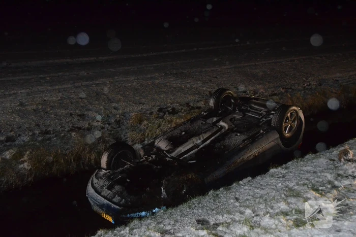 Auto glijdt van de weg en belandt op de kop in sloot