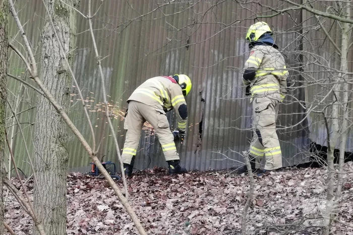 Brandweer blust brand in muur van golfplaten