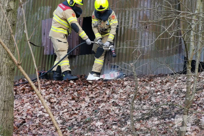 Brandweer blust brand in muur van golfplaten